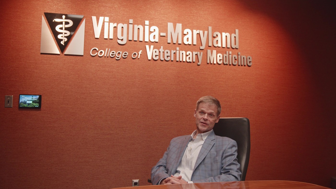 Dr. Reed Hall seated in front of the Virginia-Maryland College of Veterinary Medicine sign during his interview